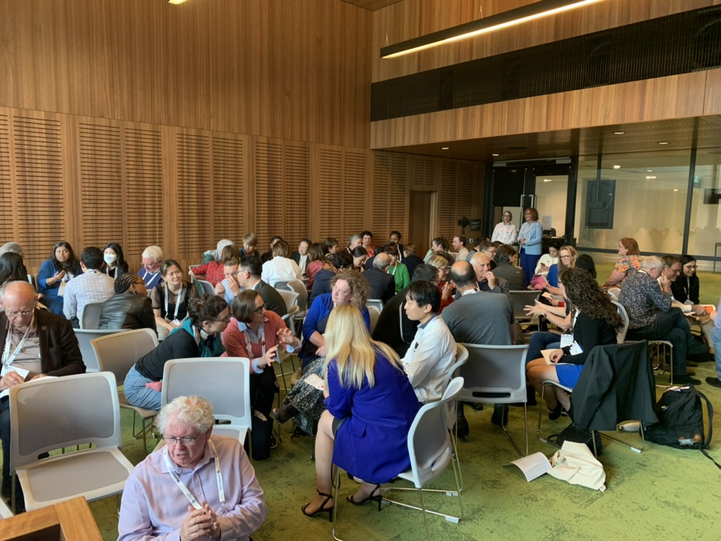 A workshop room at WONCA Sydney 2023 filled to capacity, with delegates seated in small groups in discussion